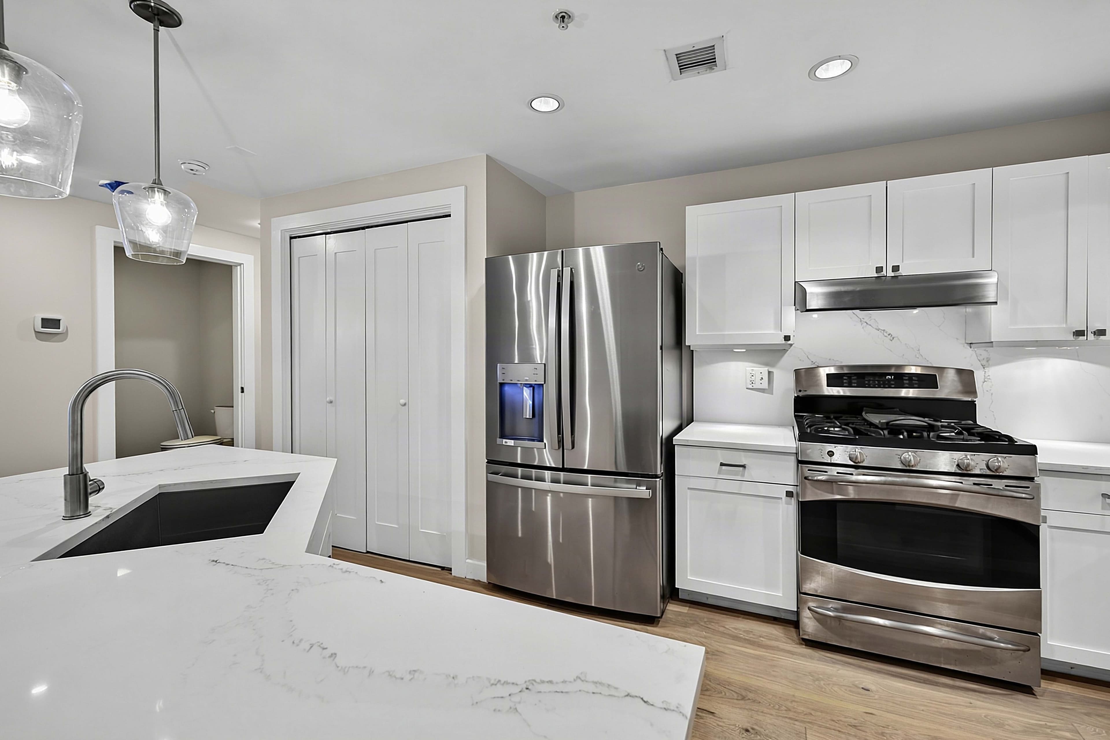 Kitchen range, refrigerator, and white cabinetry beside the island