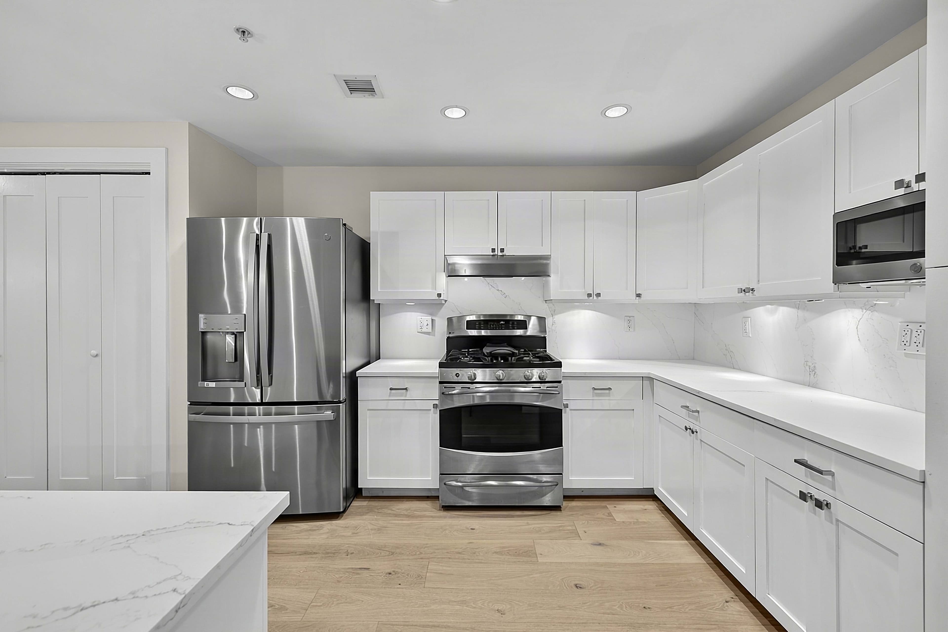 White kitchen cabinets and appliances viewed from the island