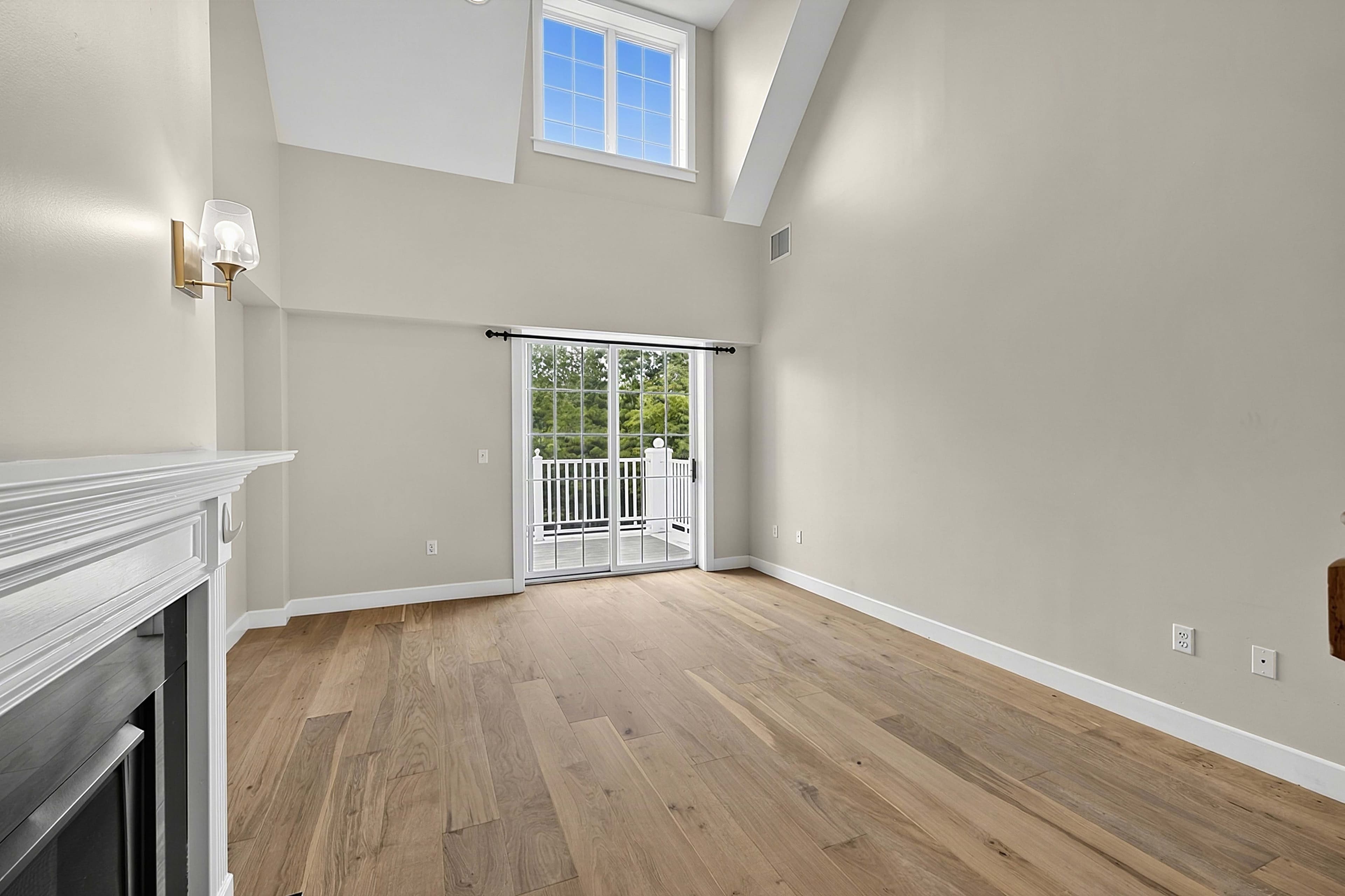 Angled view of the living room with its fireplace and balcony doors