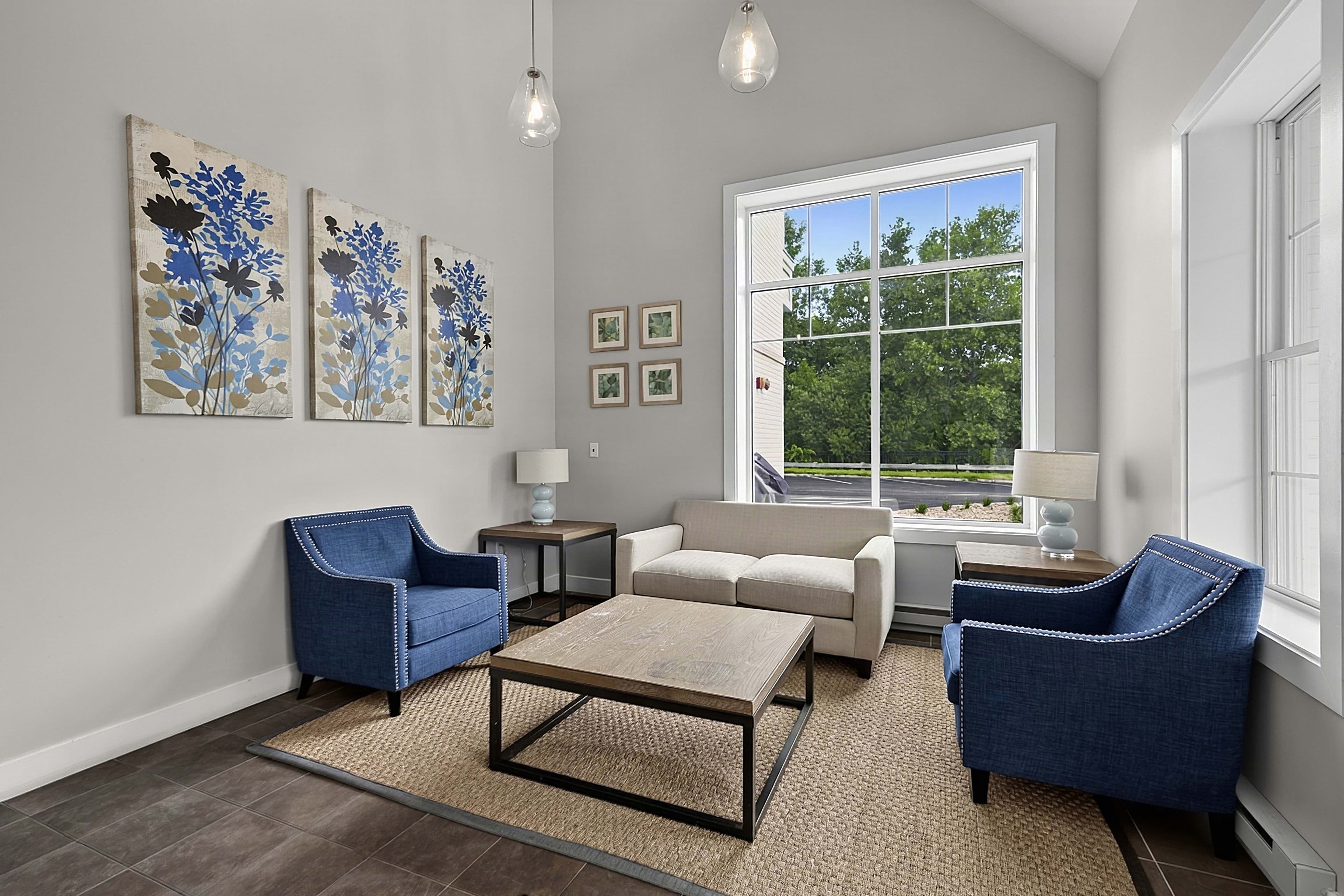Seating area with blue armchairs and a sofa beside the windows