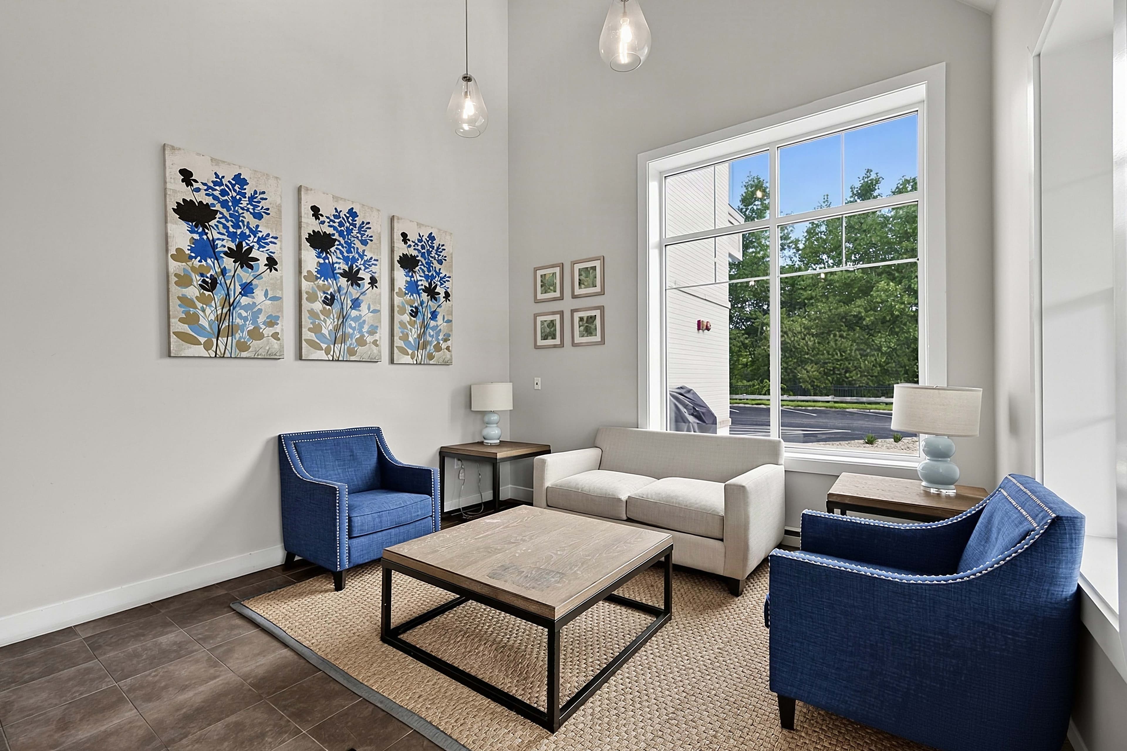 Closer view of the sofa, blue armchairs, and large window