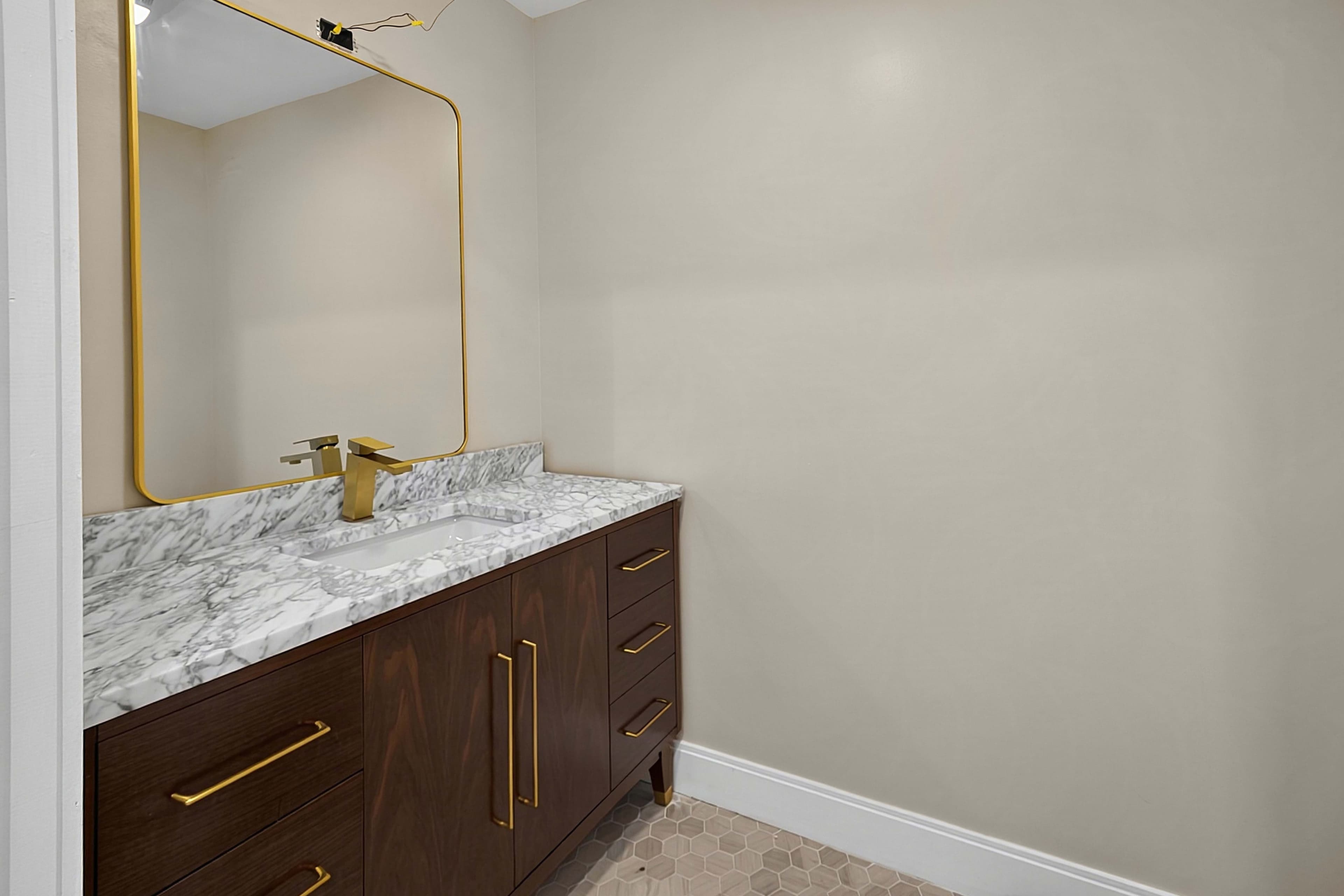 Powder room vanity with a stone countertop and brass faucet