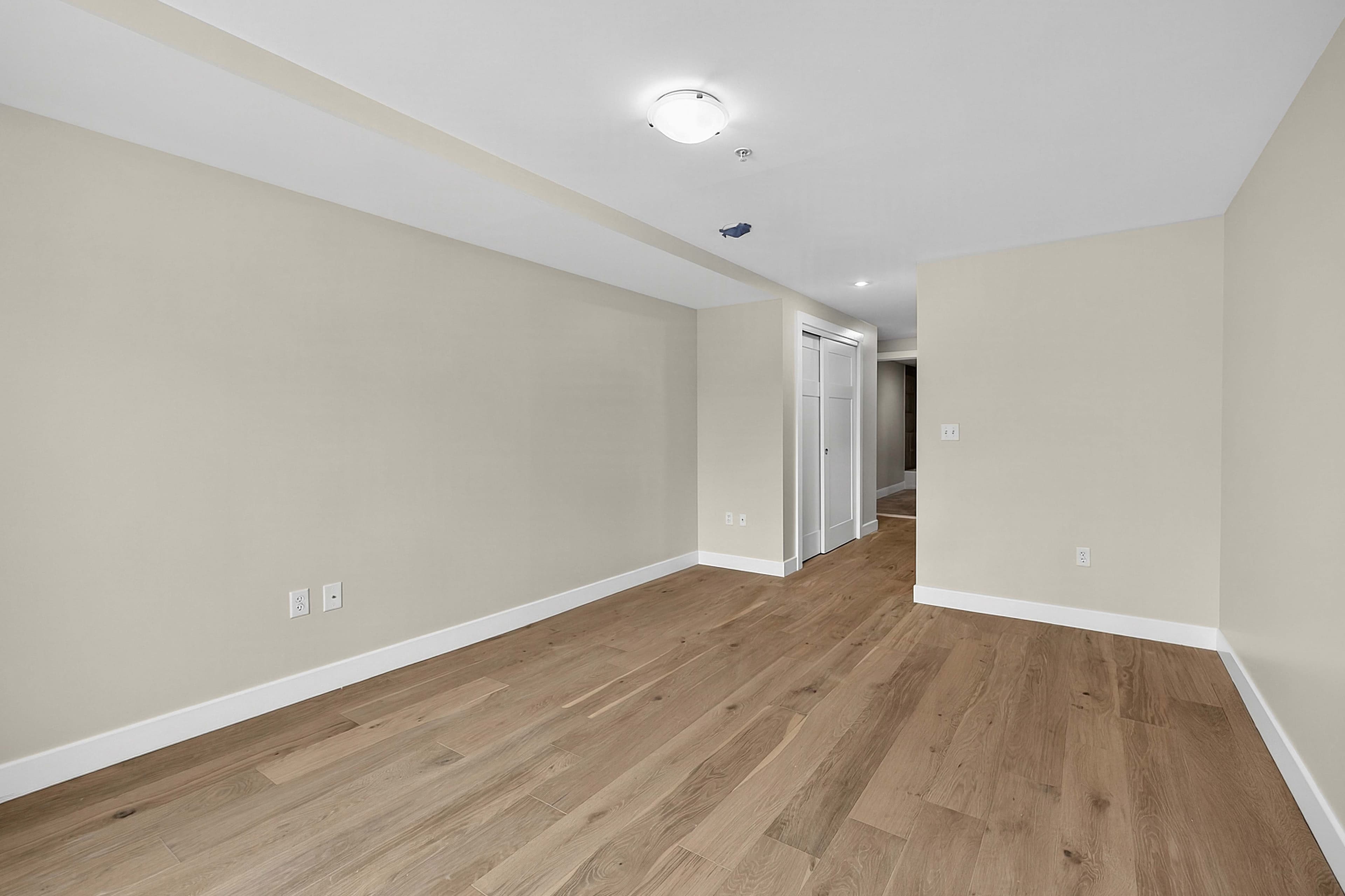Angled view of an unfurnished private room with wood flooring