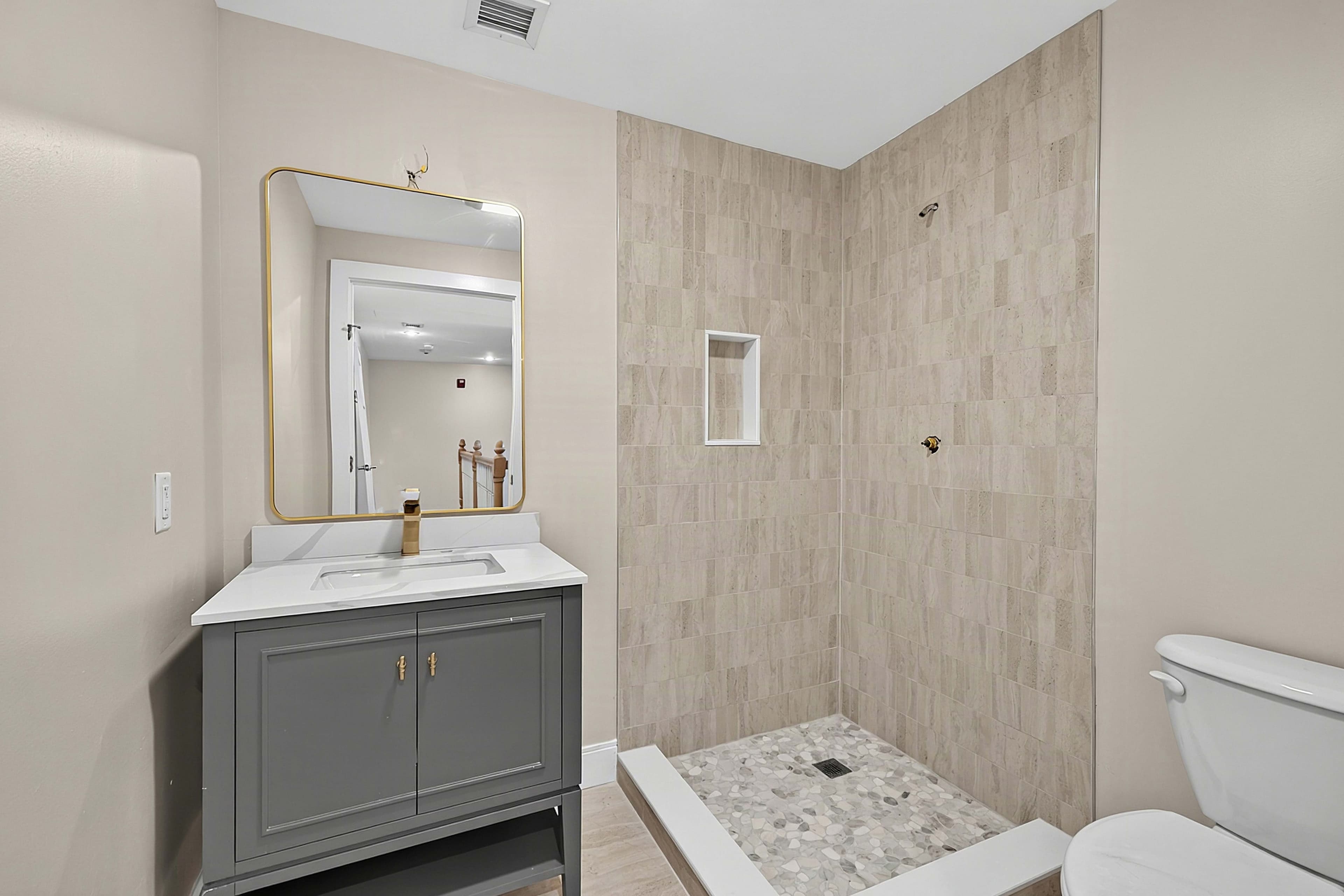 Wider view of the bathroom vanity and tiled walk-in shower